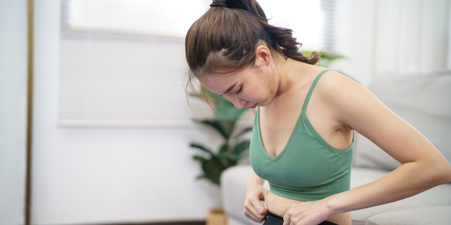 Asian woman with anorexia with measuring tape feeling unhappy