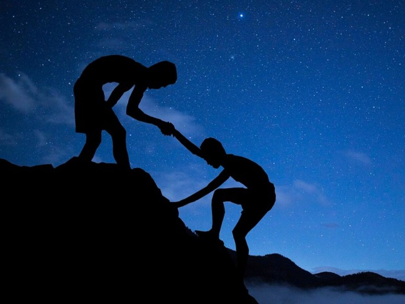 an image showing a boy helping another climb higher