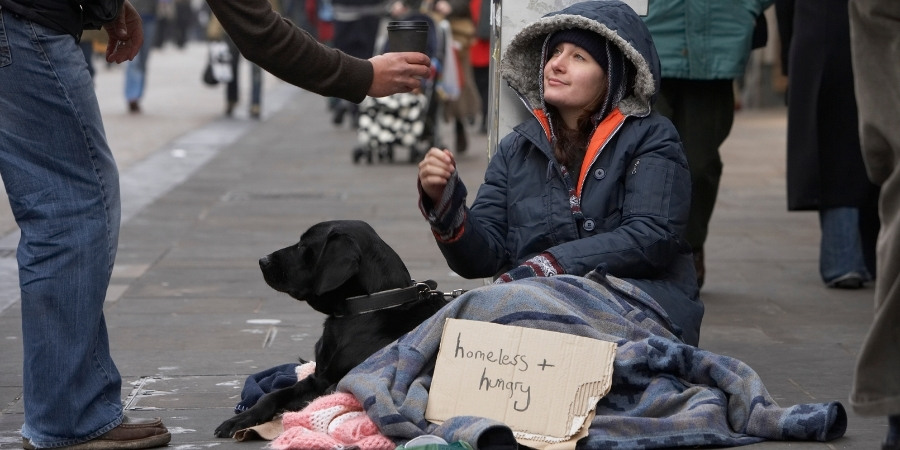 Homless woman reaching out for offered hot drink